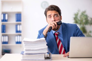 Ofisteki aşırı işten memnun olmayan genç bir erkek işçi.