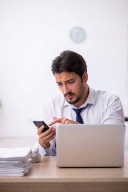 Ofisteki aşırı işten memnun olmayan genç bir erkek işçi.