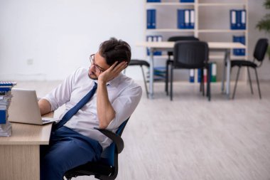 Ofisteki aşırı işten memnun olmayan genç bir erkek işçi.