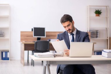 Genç erkek çalışan işyerinde oturuyor.