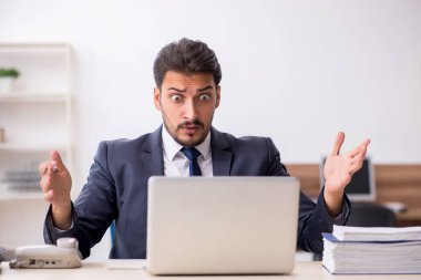 Genç erkek çalışan işyerinde oturuyor.