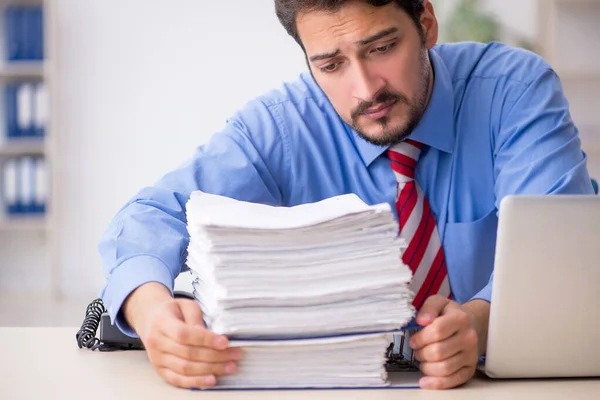 Jonge mannelijke werknemer ongelukkig met overmatig werk in het kantoor — Stockfoto