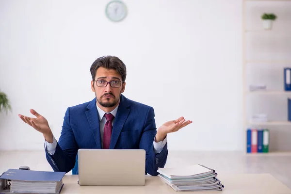 Jonge mannelijke werknemer ongelukkig met overmatig werk in het kantoor — Stockfoto