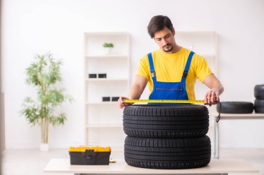 Atölyede lastiği olan genç bir erkek tamirci.