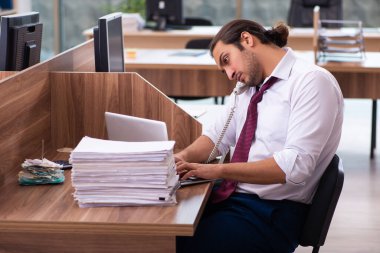 Genç bir erkek işçi ve ofiste çok fazla iş var.