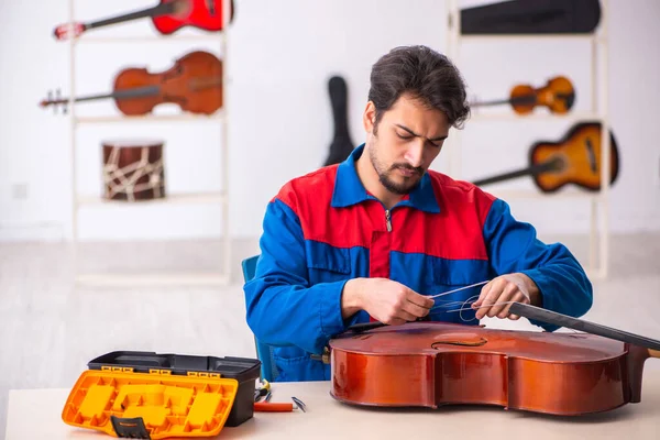Jovem reparador do sexo masculino reparando instrumentos musicais no local de trabalho — Fotografia de Stock