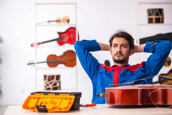 Genç erkek tamirci işyerinde müzik aletlerini tamir ediyor. — Stok fotoğraf