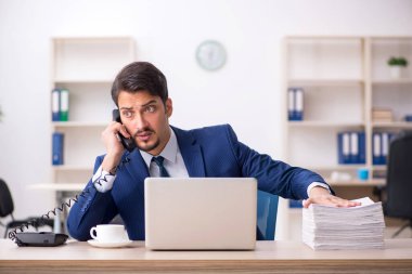 Genç bir erkek çalışan ve ofiste çok fazla iş var.