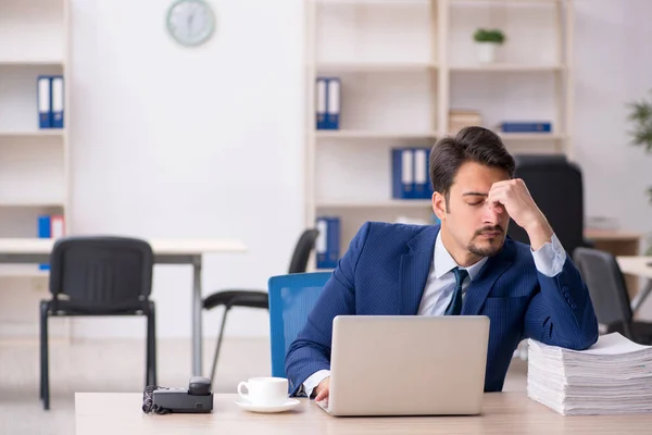 Ung manlig anställd och för mycket arbete på kontoret — Stockfoto