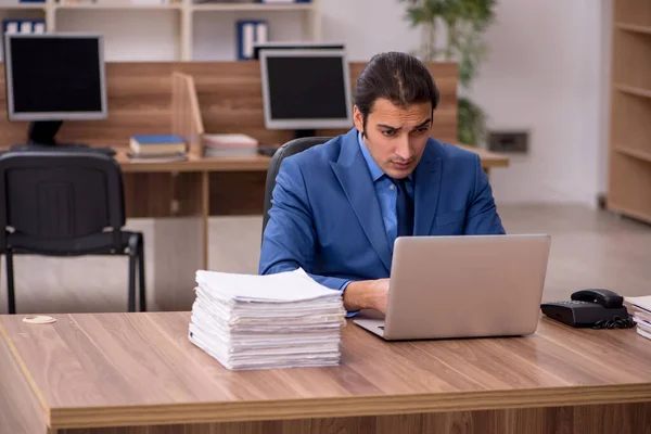 Young male employee and a lot of work in the office — Stock Photo, Image
