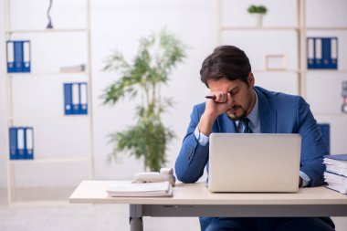 Genç bir erkek çalışan ve ofiste çok fazla iş var.