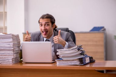 Genç bir erkek çalışan ve ofiste çok fazla iş var.