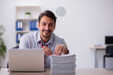 Genç erkek çalışan işyerinde oturuyor.