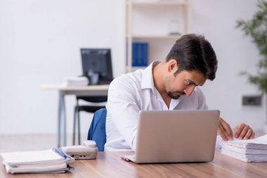 Genç bir erkek çalışan ve ofiste çok fazla iş var.