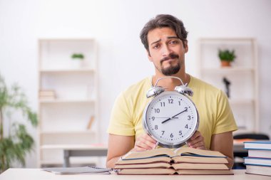 Genç erkek öğrenci zaman yönetimi konsepti sınavlarına hazırlanıyor.
