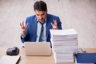 Ofisteki aşırı işten memnun olmayan genç bir erkek işçi.