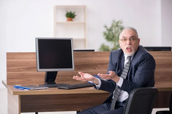 Hombre anciano empleado sentado en el lugar de trabajo — Foto de Stock