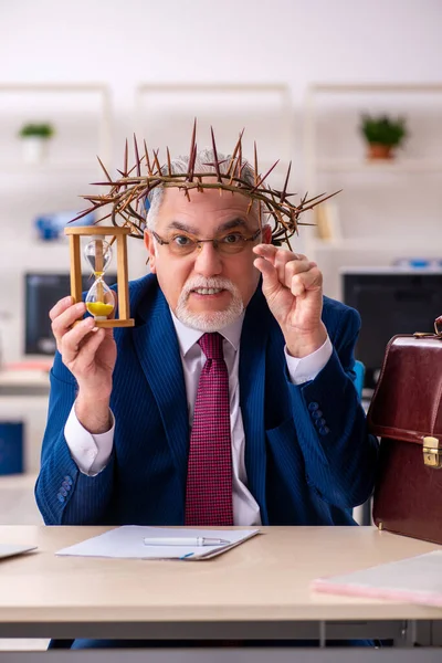 Viejo empleado masculino usando corona espinosa en concepto de gestión del tiempo — Foto de Stock