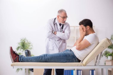 Genç erkek hasta yaşlı erkek doktoru ziyaret ediyor.