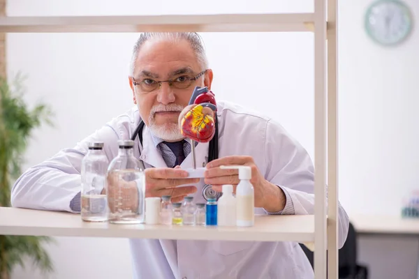 Viejo médico cardiólogo que trabaja en la clínica — Foto de Stock