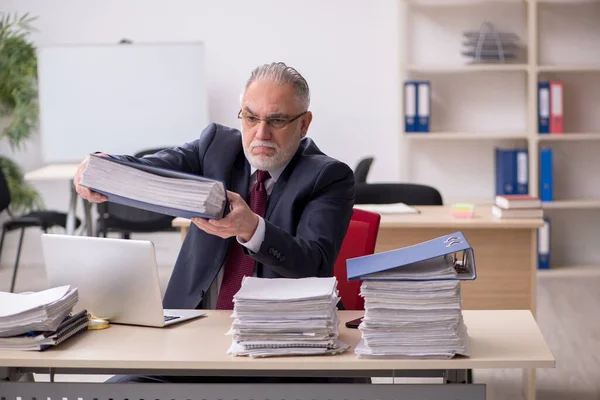 Überalterte männliche Mitarbeiter und zu viel Arbeit am Arbeitsplatz — Stockfoto