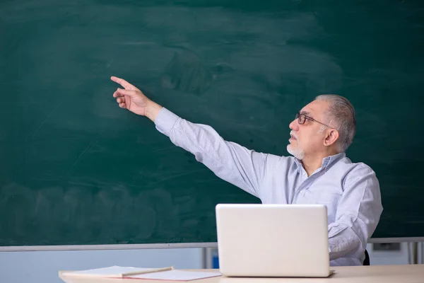 Gammal manlig lärare framför green board — Stockfoto