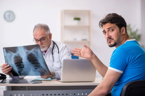 Jovem paciente masculino visitando velho médico radiologista masculino — Fotografia de Stock