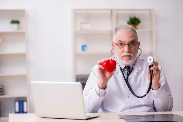 Old male doctor cardiologist working in the clinic — Stock Photo, Image