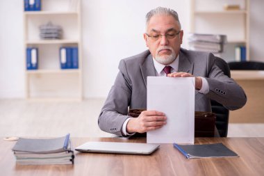 Ofiste çalışan yaşlı bir erkek.