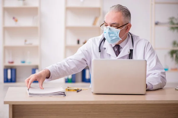 Médico do sexo masculino que trabalha na clínica durante a pandemia — Fotografia de Stock