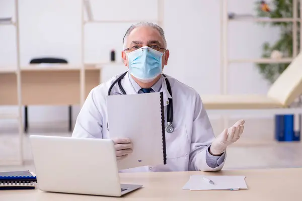 Oude mannelijke arts werkzaam in de kliniek — Stockfoto