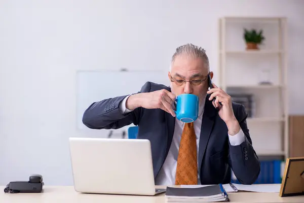 Oude mannelijke werknemer die koffie drinkt tijdens de pauze — Stockfoto