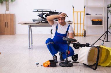 Genç erkek tamirci perambulator tamir ediyor.