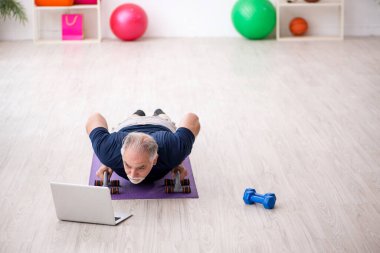 Yaşlı adam içeride spor egzersizleri yapıyor.