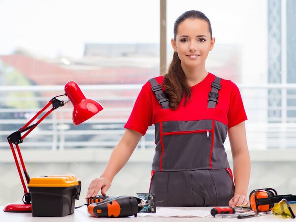 Молодая женщина в комбинезоне занимается ремонтом
