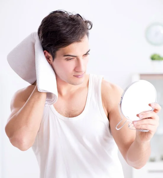 Jovem homem bonito olhando no espelho — Fotografia de Stock