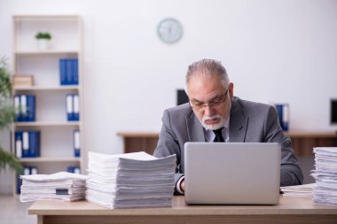 Ofisteki aşırı işten memnun olmayan yaşlı bir erkek işçi.