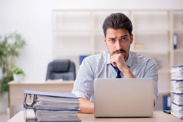 Jovem funcionário masculino e muito trabalho no escritório — Fotografia de Stock