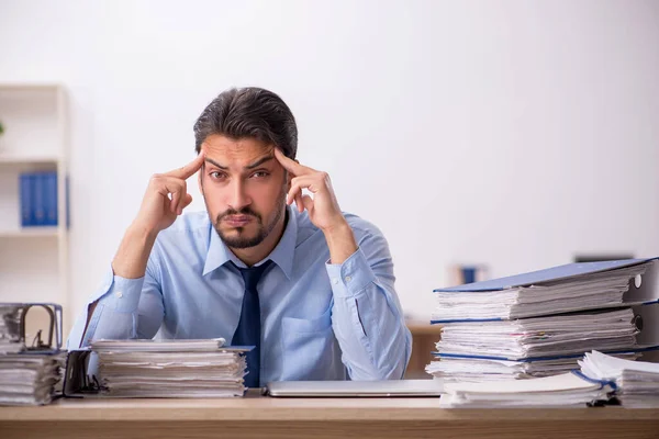 Joven empleado masculino y demasiado trabajo en la oficina — Foto de Stock