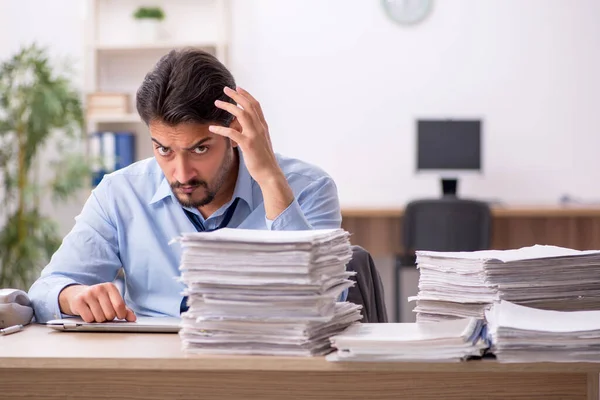 Joven empleado masculino y demasiado trabajo en la oficina — Foto de Stock