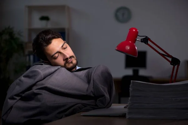 Jonge mannelijke werknemer die laat op kantoor werkt — Stockfoto