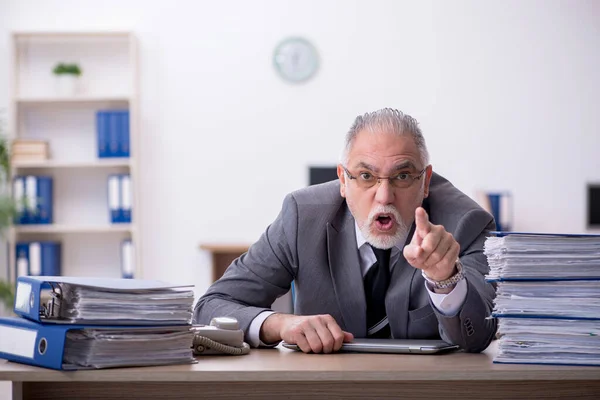 Старый работник мужчина недоволен чрезмерной работой в офисе — стоковое фото