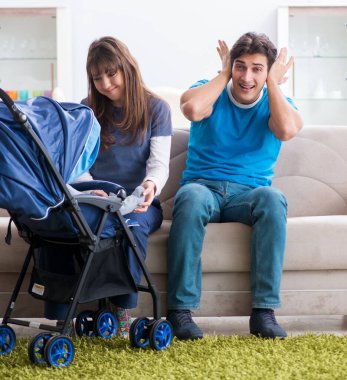 Bebekleri bebek arabasında oturan genç ebeveynler.