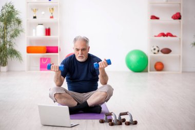Yaşlı adam içeride spor egzersizleri yapıyor.
