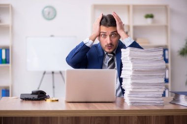 Ofisteki aşırı işten memnun olmayan genç bir erkek işçi.