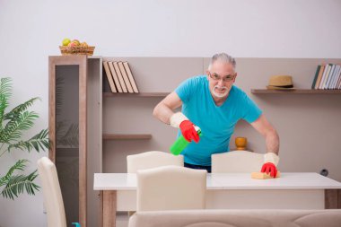 Yaşlı adam evi temizliyor.