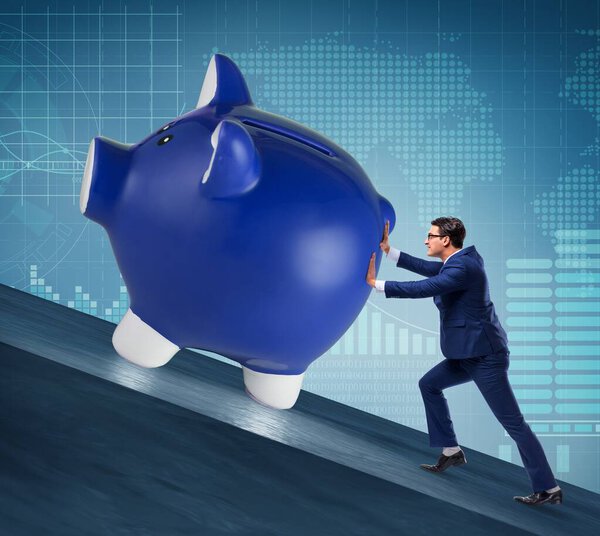 Man pushing piggybank uphill in business concept