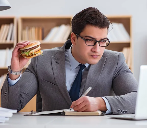 Hambriento empresario divertido comer sándwich de comida chatarra — Foto de Stock