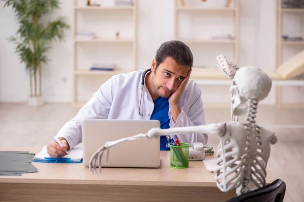 Young male doctor and skeleton patient in the clinic — Stock Photo, Image