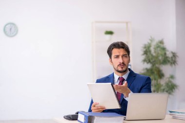 İş yerinde gazete okuyan genç bir erkek.